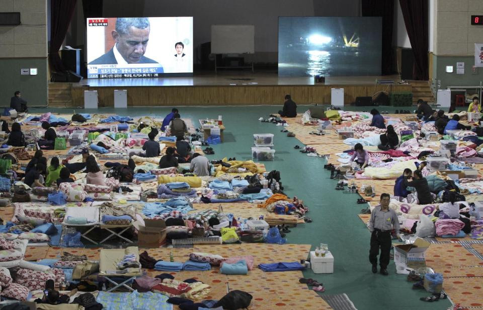 A TV screen shows U.S. President Barack Obama paying a silent tribute for the victims of South Korea's sunken ferry Sewol during a summit meeting with South Korean President Park Geun-hye as relatives of victims looks on at a gymnasium in Jindo, South Korea, Friday, April 25, 2014. As visiting Obama offered South Koreans his condolences Friday for the ferry disaster, the South Korean government conceded that some bodies have been misidentified and announced changes to prevent such mistakes from happening again. (AP Photo/Ahn Young-joon)