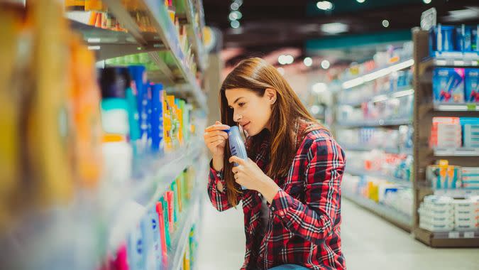 A beautiful young woman comparing two cosmetic products in the drugstore aisle of the grocery store.