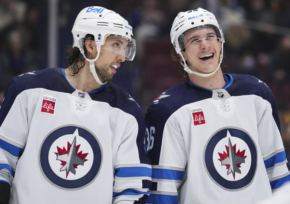 Winnipeg Jets' Brenden Dillon, left, and Morgan Barron talk before a faceoff against the Vancouver Canucks during the third period of an NHL hockey game, Saturday, Dec. 17, 2022 in Vancouver, British Columbia. (Darryl Dyck/The Canadian Press via AP)