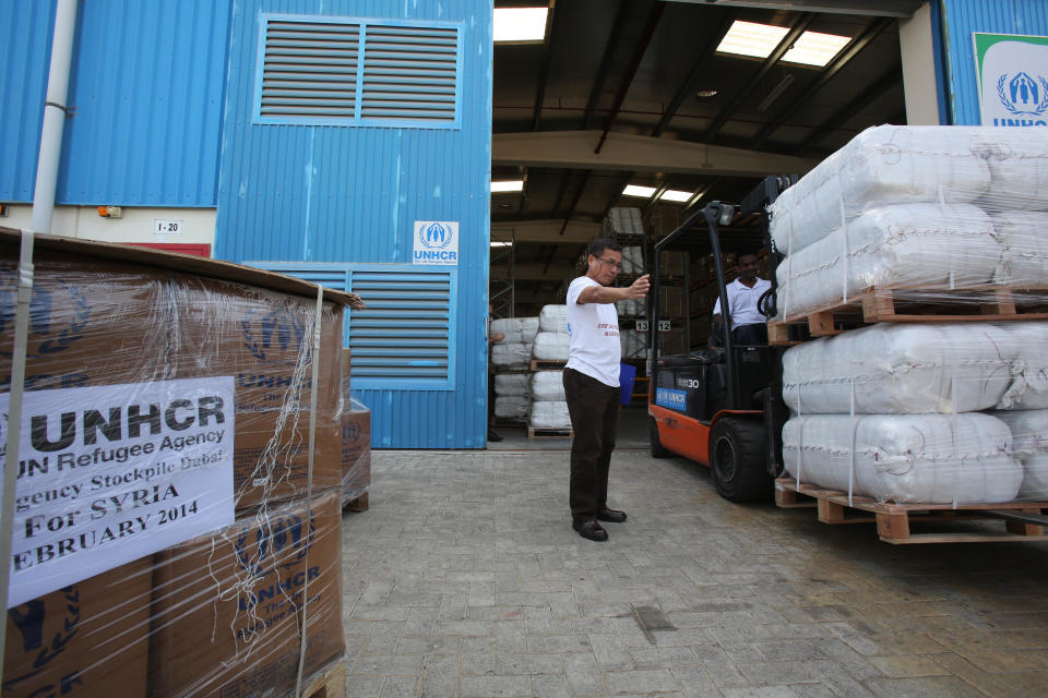 A United Nations refugee agency aid worker guides a forklift truck driver to offload its aid for Syria at the UNHCR warehouses in Dubai, part of the International Humanitarian City (IHC), the largest global stockpile for the UNHCR in Dubai, United Arab Emirates, Thursday, Feb. 20, 2014. The United Nations refugee agency said it plans to send its aid largest shipment yet to Syria. (AP Photo/Kamran Jebreili)