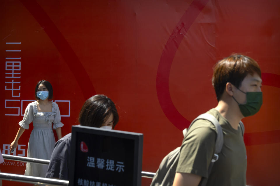 People wearing face masks walk through a shopping and office complex in Beijing, Wednesday, Aug. 24, 2022. China is easing its tight restrictions on visas after it largely suspended issuing them to students and others more than two years ago at the start of the COVID-19 pandemic. (AP Photo/Mark Schiefelbein)