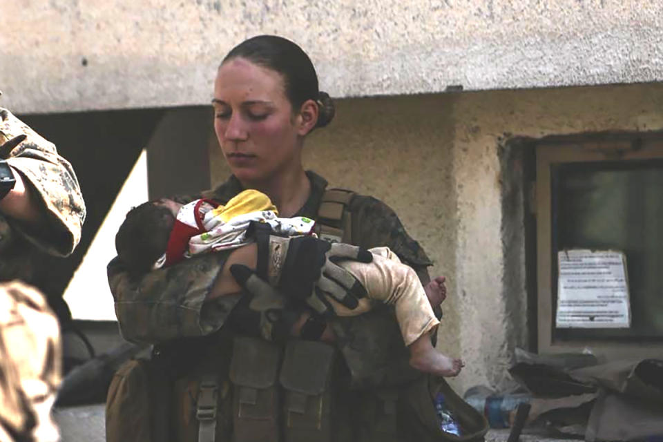 This undated photo provided by U.S. Department of Defense twitter page posted Aug. 20, 2021 shows Sgt. Nicole Gee holding a baby at Hamid Karzai International Airport in Kabul, Afghanistan. Officials said Saturday, Aug. 28, 2021, that Sgt. Nicole Gee of Sacramento, Calif., was killed in Thursday’s bombing in Kabul, Afghanistan. (U.S. Department of Defense via AP)