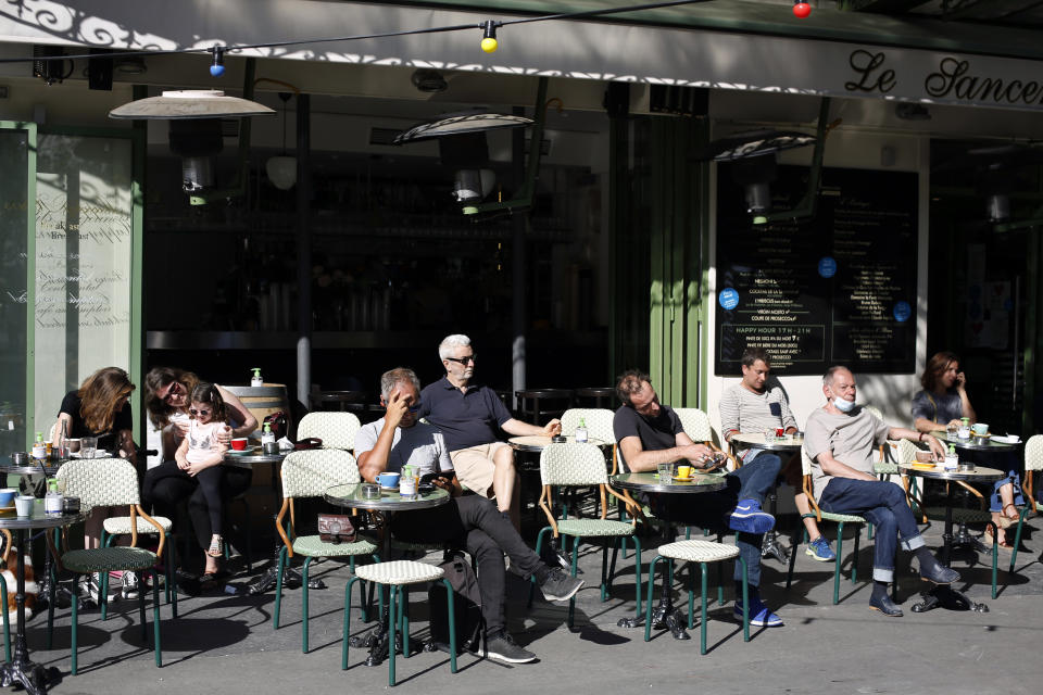 People sit on a terrace in Paris, Tuesday, June 2, 2020. Parisians who have been cooped up for months with take-out food and coffee will be able to savor their steaks tartare in the fresh air and cobbled streets of the City of Light once more -- albeit in smaller numbers. (AP Photo/Thibault Camus)