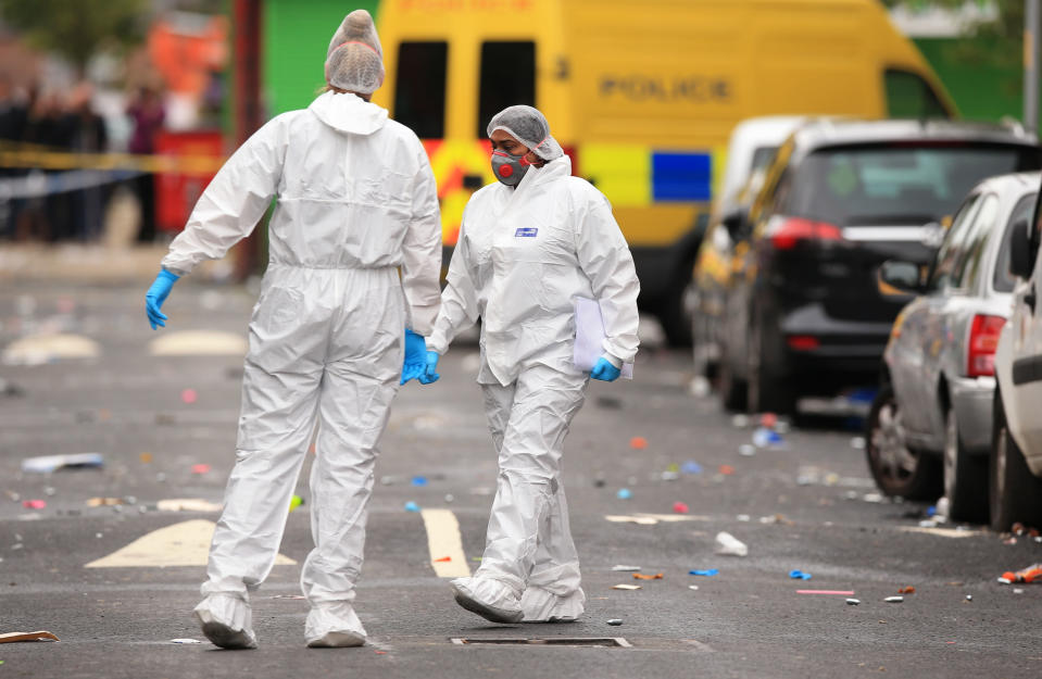 Forensic officers at the scene in the Moss Side area of Manchester, England, where several people have been injured after a shooting, early Sunday Aug. 12, 2018. Police in Manchester say 10 people have been hospitalized as the result of a shooting after a Caribbean carnival in the city. (Peter Byrne/PA via AP)