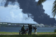 People watch a huge rising plume of smoke from the Matanzas Supertanker Base, as firefighters try to quell a blaze which began during a thunderstorm the night before, in Matazanas, Cuba, Saturday, Aug. 6, 2022. Cuban authorities say lightning struck a crude oil storage tank at the base, causing a fire that led to four explosions which injured more than 50 people. (AP Photo/Ramon Espinosa)