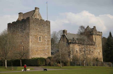 A woman walks her dogs outside Dean Castle in Kilmarnock, Scotland March 27, 2014. The Scottish capital, Edinburgh, has an air of prosperity that explains why so many of its residents are happy with their lot and unwilling to risk the changes independence may bring. REUTERS/Suzanne Plunkett