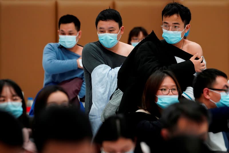 FILE PHOTO: People stand at a vaccination site after receiving a dose of a coronavirus disease (COVID-19) vaccine, in Shanghai