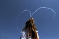 A girl sits on her father's shoulders as they watch the Turkish acrobatic aircraft jets make a heart sign in the sky, during a military parade celebration marking the 45th anniversary of the 1974 Turkish invasion in the Turkish occupied area of the divided capital Nicosia, Cyprus, Saturday, July 20, 2019. Cyprus was split into Greek Cypriot south and Turkish Cypriot north in 1974 when Turkey invaded in response to a coup by supporters of a union with Greece. (AP Photo/Petros Karadjias)