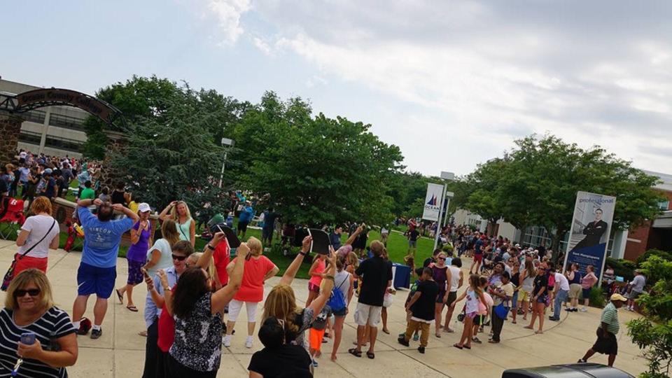 A large gathering of eclipse viewers stand outside Robert J. Novins Planetarium at Ocean County College, during the 2017 total solar eclipse.