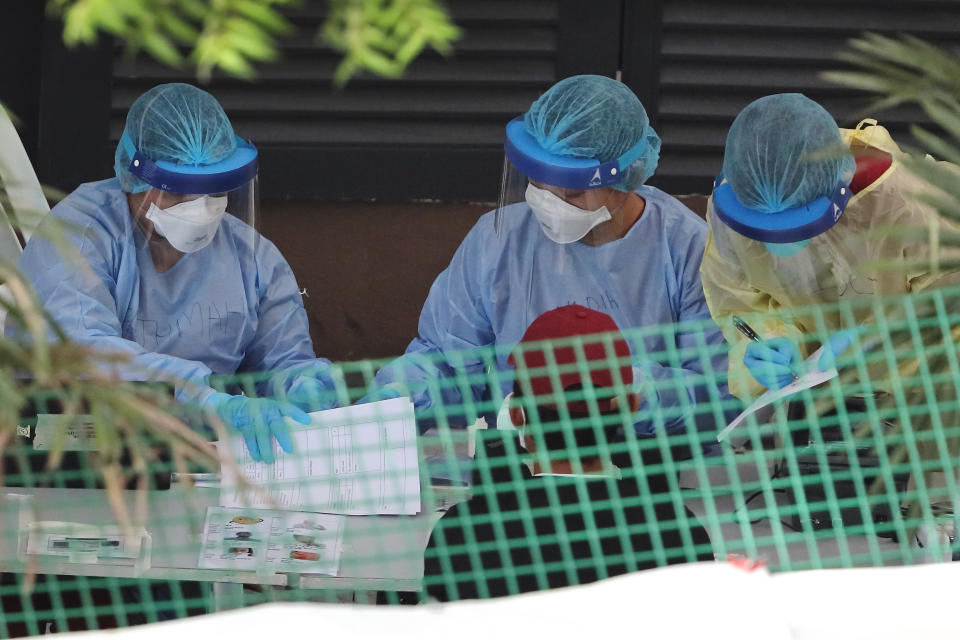 SINGAPORE - APRIL 29:  Healthcare workers wearing the personal protective equipment attend to a foreign worker at a dormitory on April 29, 2020 in Singapore. Singapore is now battling to control a huge outbreak in the coronavirus (COVID-19) local transmission cases among the migrant workers. (Photo by Suhaimi Abdullah/Getty Images)