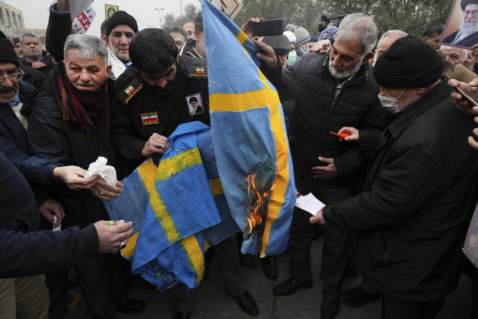 Protesters burn representations of the Swedish flag during a protest to denounce the recent desecration of Islam's holy book, Quran, by a far-right activist in Sweden, after Friday Prayers in Tehran, Iran, Friday, Jan. 27, 2023. (AP Photo/Vahid Salemi)