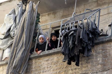 Women look out from a damaged balcony after an air strike on the rebel held al-Saliheen district in Aleppo, Syria, March 11, 2016. REUTERS/Abdalrhman Ismail