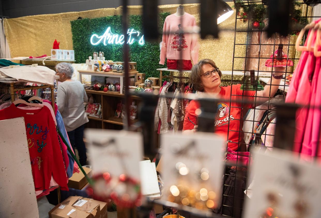 Sandra Tucker hangs up wares in the Arnett's booth to get ready for the Mistletoe Marketplace held by the Junior League of Jackson with varying events and shopping through Wednesday, Nov. 1, 2023, to Saturday, Nov. 4, 2023, at the Mississippi Trade Mart in Jackson, Miss., on Monday, Oct. 30, 2023.