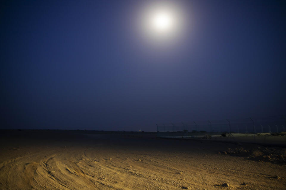 In this July 14, 2019 photo, the moon shines on the beach where smugglers move Ethiopian migrants on pick up trucks to take them on a boat to Yemen, in Obock, Djibouti. Over the past three years, the IOM reported 9,000 Ethiopians were deported each month. Many migrants have made the journey multiple times in what has become an unending loop of arrivals and deportations. (AP Photo/Nariman El-Mofty)