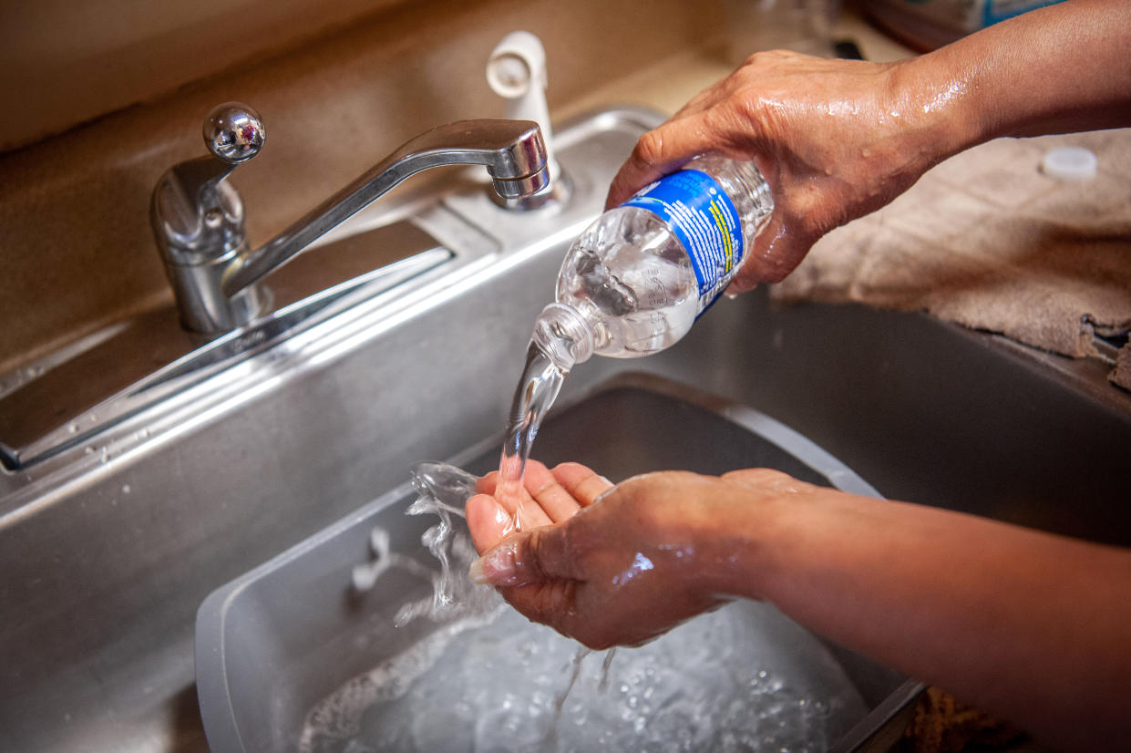 Una residente de Jackson, Misisipi, se lava las manos con agua embotellada en el fregadero de la cocina, el 11 de marzo de 2021. (Rory Doyle/The New York Times)