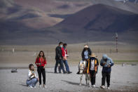 Tourists walk along the lakeshore and ride a pony in Namtso in western China's Tibet Autonomous Region, Wednesday, June 2, 2021. Tourism is booming in Tibet as more Chinese travel in-country because of the coronavirus pandemic, posing risks to the region's fragile environment and historic sites. (AP Photo/Mark Schiefelbein)