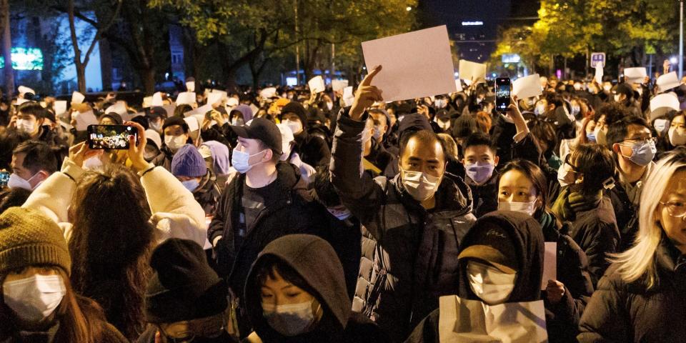 People hold white sheets of paper in protest of COVID-19 restrictions in Beijing, China, on November 27, 2022.