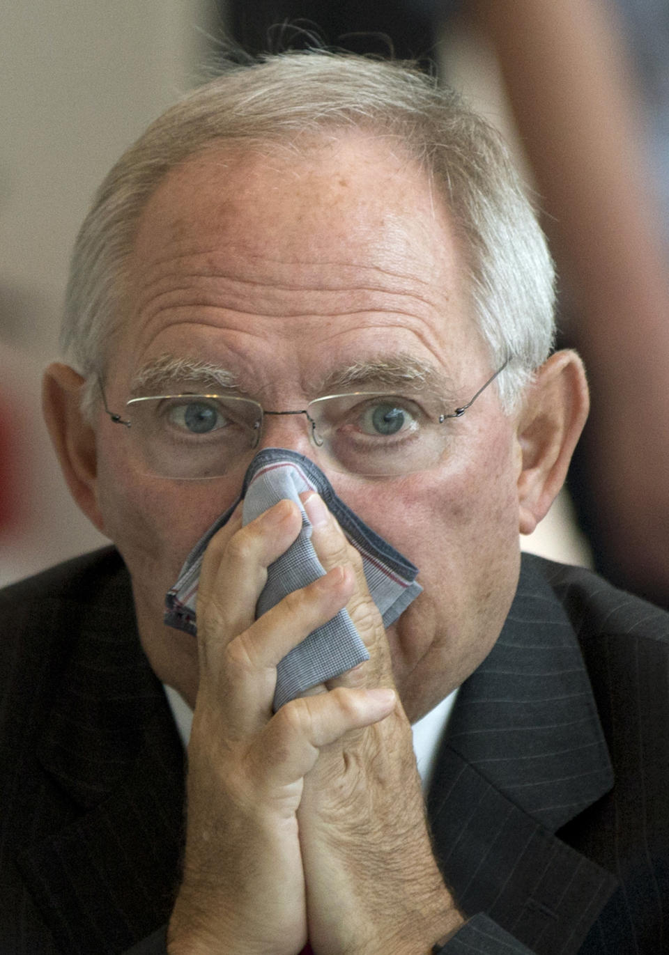 German Finance Minister Wolfgang Schaeuble wipes his nose before a meeting of the CDU/CSU parliamentary parties prior to a special session of the Germany Parliament Bundestag in Berlin, Germany, Thursday, July 19, 2012. Germany's Parliament is interrupting its summer break to vote on a rescue package worth up to euro 100 billion (US dollar122 billion) for Spain's ailing banks. (AP Photo/Gero Breloer)