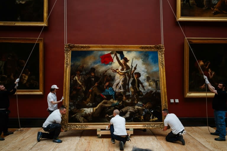 Louvre employees hang a brighter 'Liberty Leading the People' back in place (Dimitar DILKOFF)