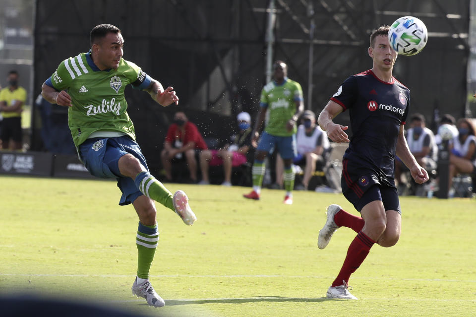 Seattle Sounders midfielder Miguel Ibarra, left, takes a shot on goal as Chicago Fire midfielder Fabian Herbers, right, tries to defend during the first half of an MLS soccer match, Tuesday, July 14, 2020, in Kissimmee, Fla. (AP Photo/John Raoux)