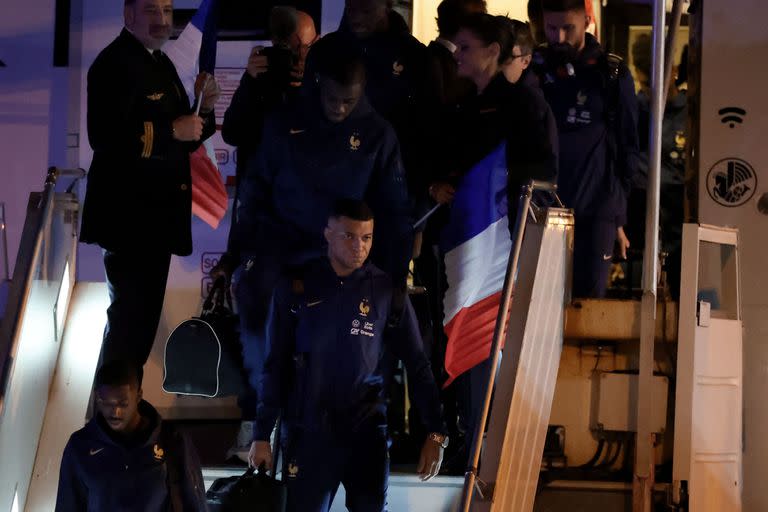 El delantero de Francia Ousmane Dembele (botL) y el delantero Kylian Mbappe (C) salen de un avión de AirFrance mientras el equipo nacional francés llega al aeropuerto de Roissy-Charles-de-Gaulle en las afueras de París, regresando de Qatar después de perder el partido de fútbol final de la Copa del Mundo 2022 contra Argentina, el 19 de diciembre de 2022.