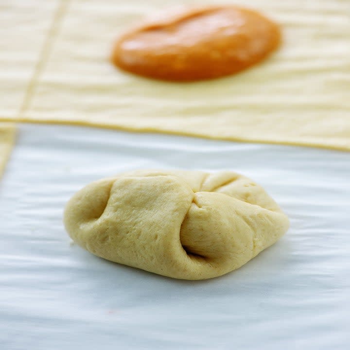 Folding a piece of dough filled with pumpkin filling.