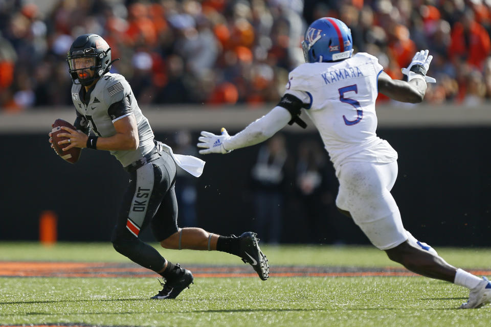 STILLWATER, OK - NOVEMBER 16:  Quarterback Spencer Sanders #3 of the Oklahoma State Cowboys rolls out to avoid linebacker Azur Kamara #5 of the Kansas Jayhawks in the first quarter on November 16, 2019 at Boone Pickens Stadium in Stillwater, Oklahoma.  OSU won 31-13.  (Photo by Brian Bahr/Getty Images)