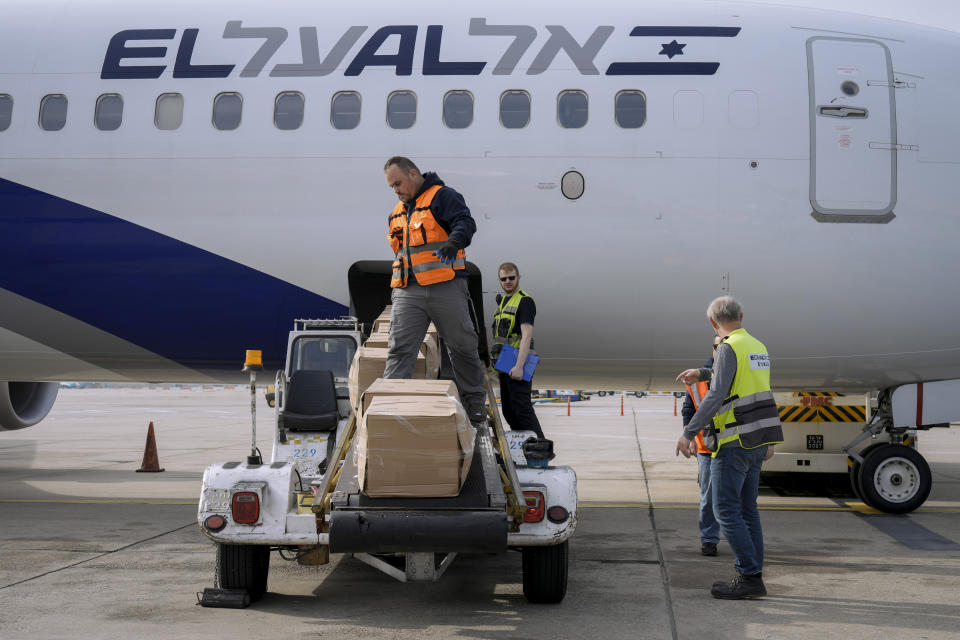 FILE - Workers load packages of Israeli humanitarian aid to assist people caught up in the fighting in Ukraine, in Ben Gurion airport in Lod, Israel, on March 1, 2022. When Russian forces two months ago launched a military campaign against infrastructure in Ukraine, it opened an urgent second front far from the contact line: along power lines, water mains, and heating systems, and in places like homes, schools, offices and churches. (AP Photo/Tsafrir Abayov, File)