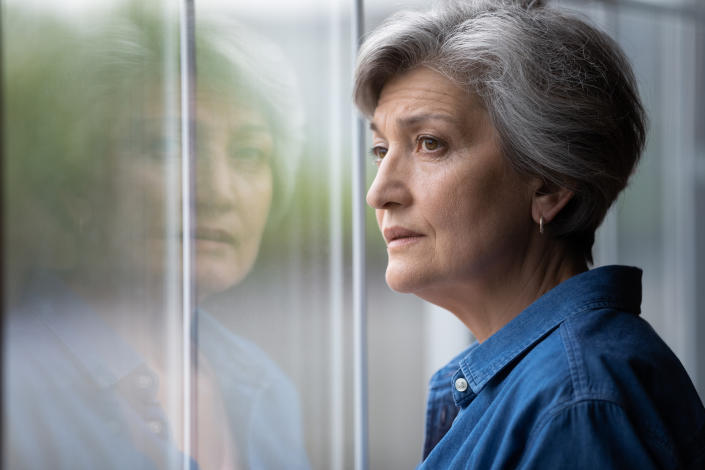 Older woman looking wistfully out of window