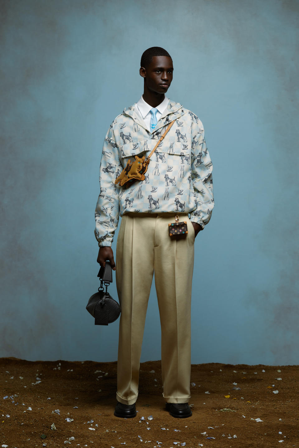 A model wears a windbreaker with a pattern of Airedale Terriers and a dog-shaped strap bag from the Louis Vuitton spring 2024 men's capsule collection by Tyler, the Creator.