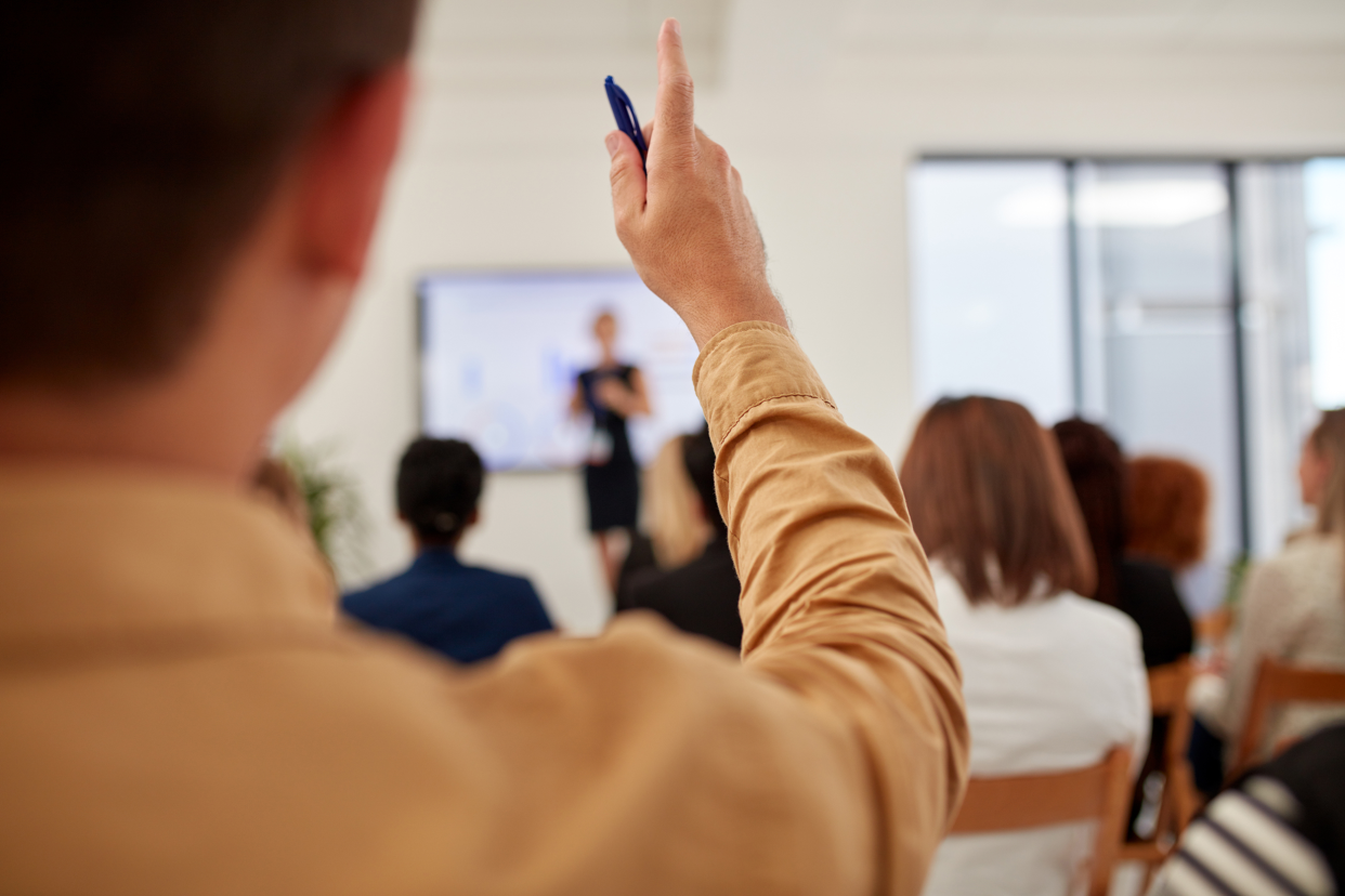 Man in a meeting raising his hand