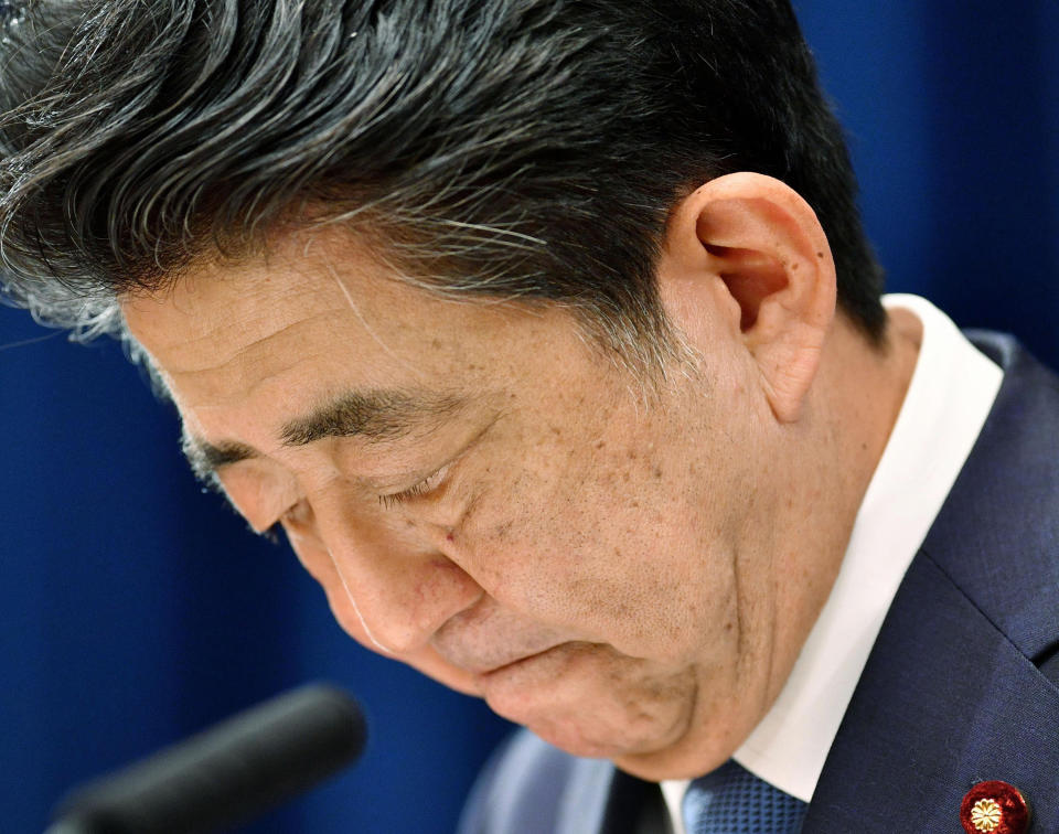 Japanese Prime Minister Shinzo Abe downs his head as he says he is stepping down during a press conference at the prime minister official residence in Tokyo Friday, Aug. 28, 2020. Japan's longest-serving prime minister Abe said Friday he intends to step down because a chronic health problem has resurfaced. He told reporters that it was “gut wrenching” to leave so many of his goals unfinished. (Kyodo News via AP)