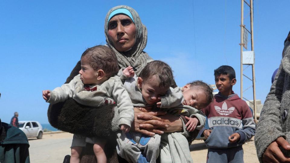 PHOTO: Palestinian woman Nozha Awad flees Al Shifa hospital following an Israeli raid with her triplet children, moving southward in the central Gaza Strip, March 21, 2024.  (Ramadan Abed/Reuters)