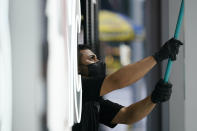 A worker cleans a display window at the MLB Flagship store Wednesday, Sept. 30, 2020, in New York. Inside a former Manhattan television studio, the scaffolding has come down and Major League Baseball’s first retail store opens Friday across from Radio City Music Hall in a part of Midtown Manhattan largely emptied by the coronavirus pandemic.(AP Photo/Frank Franklin II)