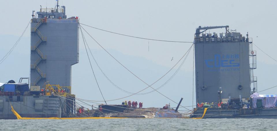 Workers prepare to lift the sunken Sewol ferry, center, in waters off Jindo, South Korea, Thursday, March 23, 2017. A 6,800-ton South Korean ferry emerged from the water on Thursday, nearly three years after it capsized and sank into violent seas off the country's southwestern coast, an emotional moment for the country that continues to search for closure to one of its deadliest disasters ever. (Yonhap via AP)