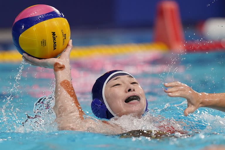 La china Xinyan Wang pasa el balón mientras se aleja de un defensor durante un partido de waterpolo femenino de la ronda preliminar contra Estados Unidos en los Juegos Olímpicos de Verano de 2020, el lunes 26 de julio de 2021, en Tokio, Japón.