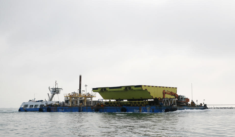 A yellow barrier, part of a plan to protect the city of Venice from flooding, floats on a barge, in Venice, Italy, Friday, Nov. 29, 2019. In the wake of last month’s flooding of Venice, the worst in 53 years, the consortium that oversees construction of the Moses is eager to demonstrate that the project, after years of bad news, is on track and will be fully operational by the end of 2021. (AP Photo/Antonio Calanni)