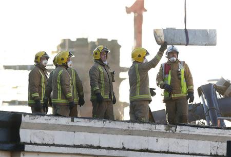 Rescue workers lift a rotor blade from the site of a police helicopter crash onto the Clutha Pub in central Glasgow, Scotland, December 1, 2013. REUTERS/Andrew Winning