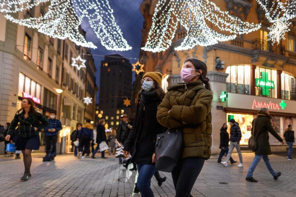 People wear face masks while walking under Christmas lights in the centre of Lausanne in Switzerland (AFP via Getty Images)