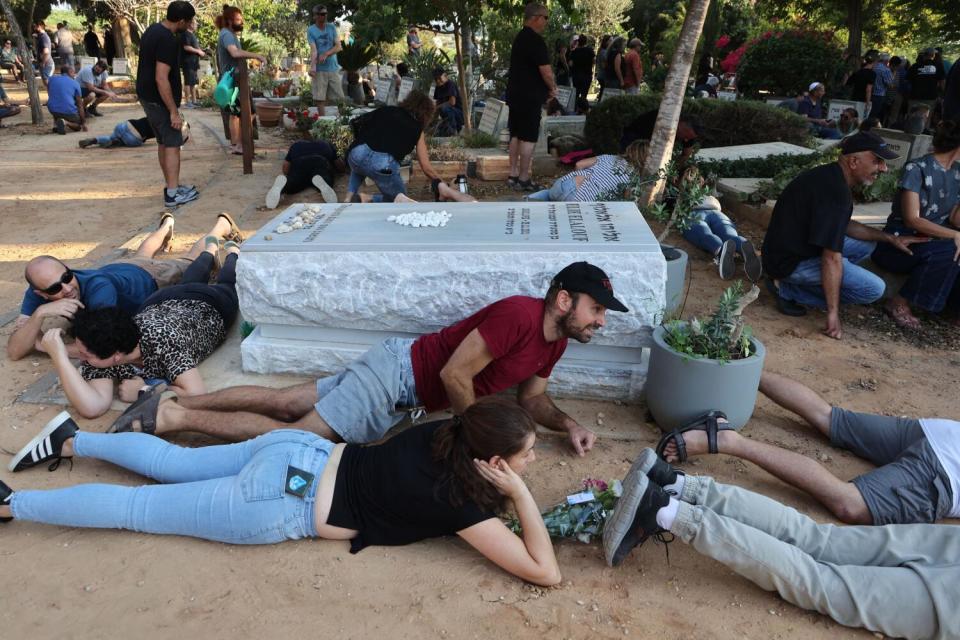 Mourners duck for cover upon hearing sirens warning of incoming rockets during the funeral of Tom Godo.