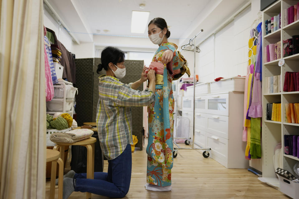 A Japanese woman gets help to wear kimono at Daikichi kimono rental shop Wednesday, June 22, 2022, in Tokyo's Asakusa area famous for sightseeing, before attending her family friend's wedding. Japan is bracing for a return of tourists from abroad, as border controls to curb the spread of coronavirus infections are gradually loosened. Yusuke Otomo, who owns the kimono rental shop, can barely contain his excitement. (AP Photo/Hiro Komae)