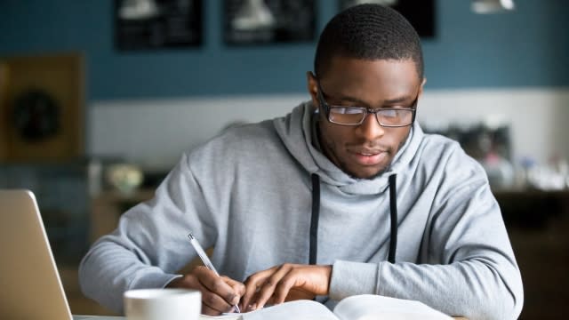 College student taking notes from a textbook