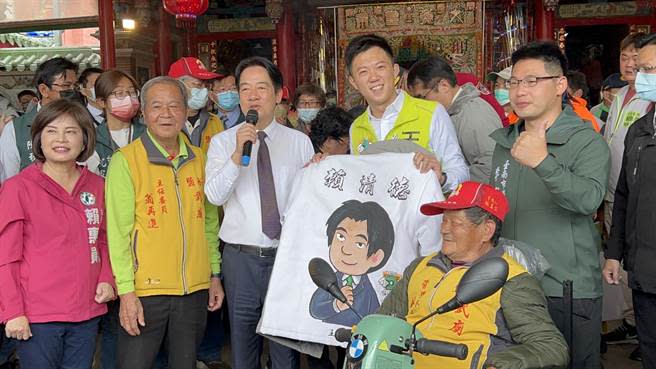 民進黨台南市議員王宣貿（左四）致贈印有賴清得Q版圖樣的蜂炮衣，賴（左三）收到時臉上露出燦爛的笑容。（張毓翎攝）