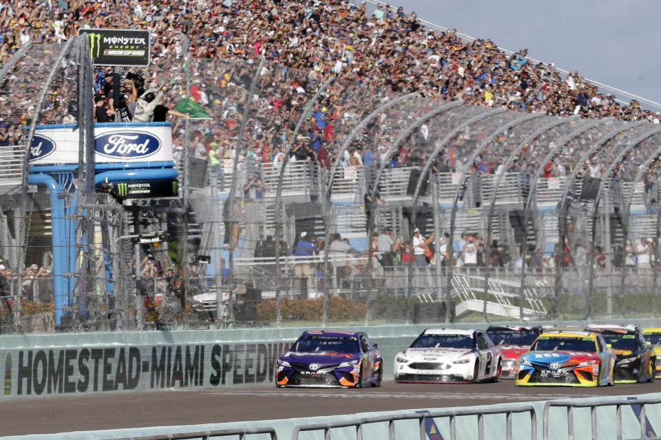 FILE - In this Nov. 18, 2018, file photo, Denny Hamlin, left, leads the pack at the start of the NASCAR Cup Series championship auto race at Homestead-Miami Speedway, in Homestead, Fla. NASCAR and IndyCar have each called off their races this weekend. NASCAR was scheduled to run Sunday at Atlanta Motor Speedway without spectators but said Friday, March 13, 2020, it is calling off this weekend and next week’s race at Homestead-Miami Speedway. IndyCar was scheduled to open its season Sunday on the streets of St. Petersburg, Florida, but suspended it’s season through the end of April. (AP Photo/Lynne Sladky, File)