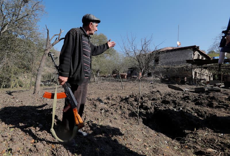 Local resident Alexei Agadzhanov shows a crater following recent shelling in Shosh