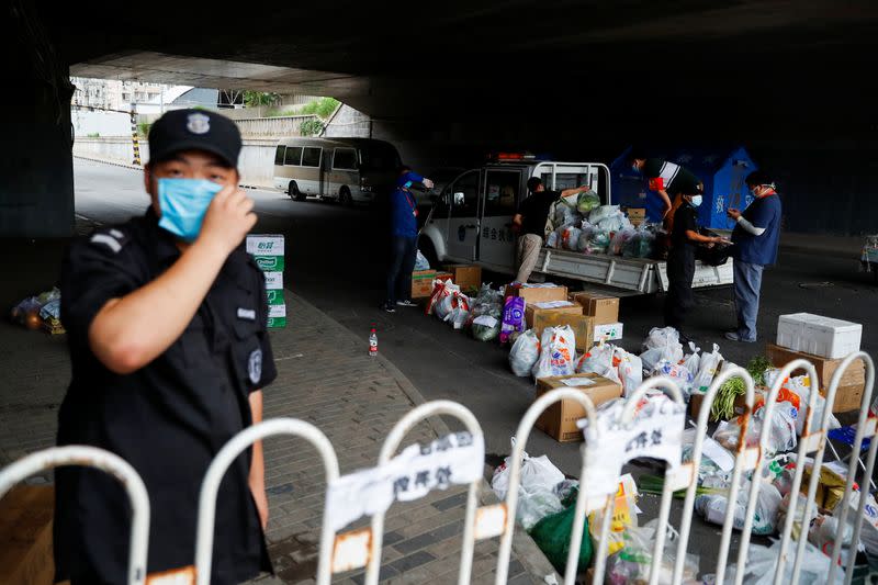 People deliver food near a residential compound that is under lockdown in the Fengtai district, in Beijing
