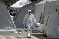 A health worker wearing protective suits walks in between tents at a parking lot that has been converted into an extension of the Gat Andres Bonifacio Memorial Medical Center in Manila, Philippines on Monday, Aug. 3, 2020. Philippine President Rodrigo Duterte is reimposing a moderate lockdown in the capital and outlying provinces after medical groups appealed for the move as coronavirus infections surge alarmingly. (AP Photo/Aaron Favila)