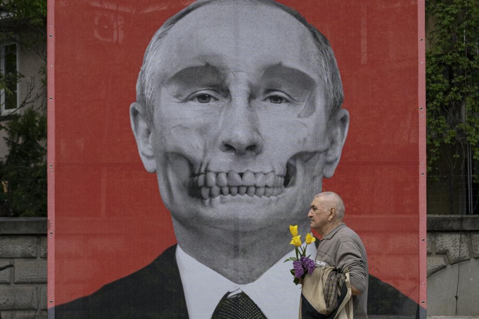<span class="caption">A man walks by a depiction of Russian President Vladimir Putin with skeleton teeth by artist Krišs Salmanis outside the Russian Embassy in Bucharest, Romania, April 29, 2022.</span> <span class="attribution"><span class="source">(AP Photo/Vadim Ghirda)</span></span>