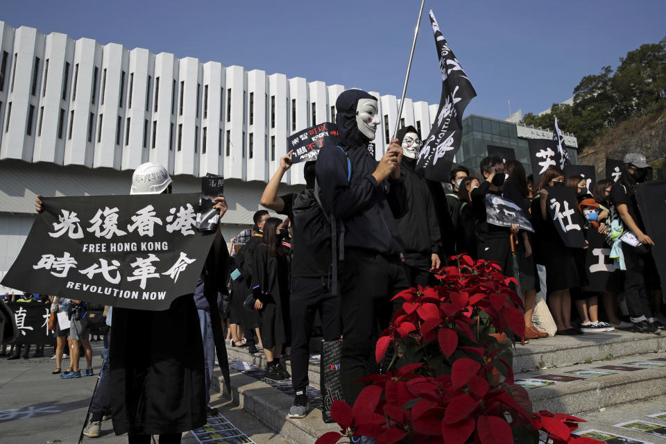 University students wearing Guy Fawkes masks, hold banners as they protest against the government before their graduation ceremony at the Chinese University of Hong Kong, Thursday, Nov. 7, 2019, in Hong Kong. (AP Photo/Kin Cheung)