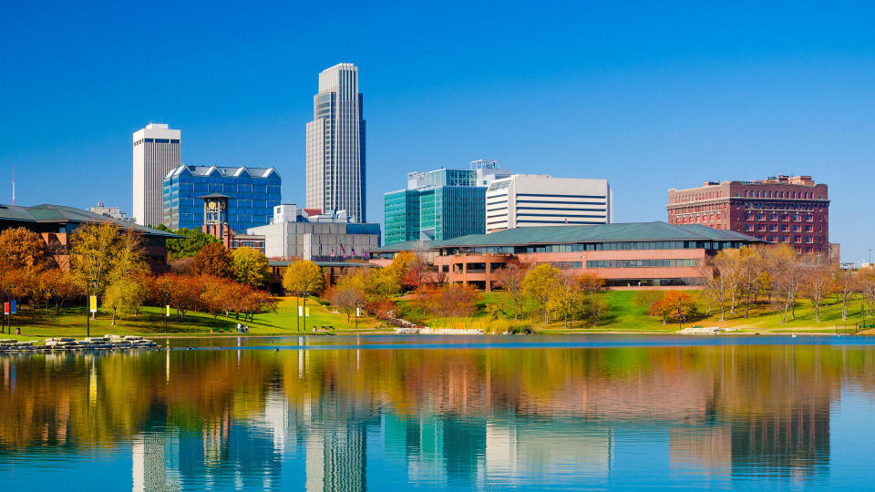 Omaha downtown skyline during Autumn, with a lake at the Heartland of America Park in the foreground.
